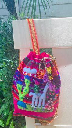 a colorful purse hanging on a white bench