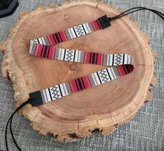 two red and white bracelets sitting on top of a piece of wood next to a charger