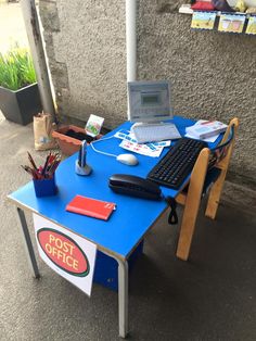 a blue desk with a laptop on it and a post office sign under the table