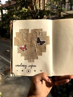 someone holding up an open book with two butterflies on it and the pages have been torn off