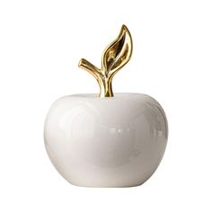 a white apple with a gold leaf decoration on the top is shown in front of a white background