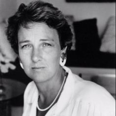 an old black and white photo of a woman with pearls on her necklace sitting in a living room