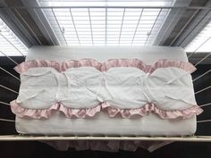 a white crib with pink ruffles on it