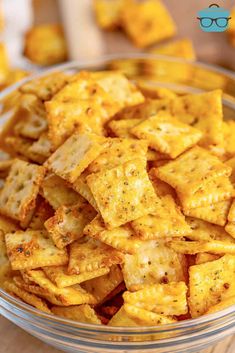 a glass bowl filled with cheesy crackers on top of a wooden table