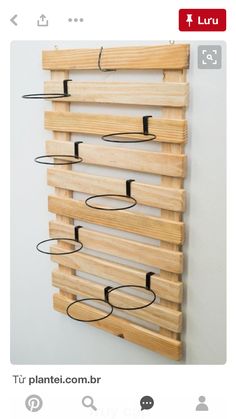 a wooden rack with metal rings hanging from it's sides on a white wall