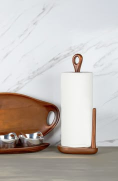 a wooden tray with two cups and spoons on it next to a white marble wall