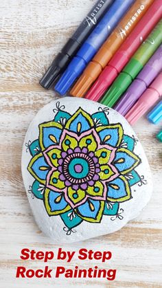 colorful markers and rocks are sitting next to each other on a wooden table with pens