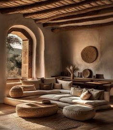 a living room filled with furniture and a large window overlooking the desert landscape in an adobe - style home