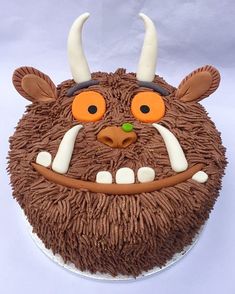 a cake decorated to look like a monster's head with horns and big eyes