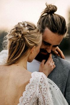 a man and woman standing next to each other in front of the camera with their hair pulled back