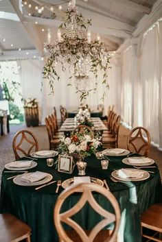 an elegant table setting with green linens and greenery on the centerpiece is surrounded by white flowers