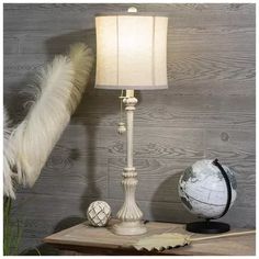 a lamp that is sitting on top of a table next to a ball and feather