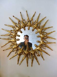 a man is taking a selfie in front of a gold sunburst mirror