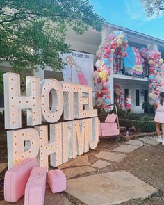 a woman standing in front of a sign that says hotel bhimu with pink suitcases