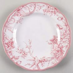 a pink and white plate with floral designs on it, sitting on a gray surface