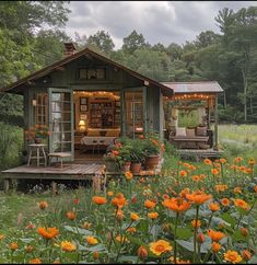 a small cabin in the middle of a field with orange flowers and lights on it