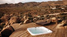 a large hot tub sitting on top of a wooden deck next to rocks and trees