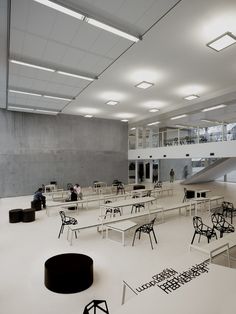 an empty room with tables and chairs in the center, some people are walking around