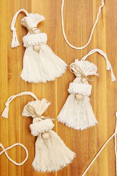 three white tasselled bags on a wooden floor next to some string and wood pegs