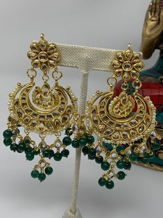 These gorgeous Kundan earrings are featured with amazing combination of Kundan work and green beads.  Made on brass base metal and then gold plated. Approximate length of the earrings is 4 inches and width is ~2inches We carefully inspect each piece before shipping and package in cotton padded box to ensure it arrives safely. All orders are shipped free using USPS, Fedex or UPS.  Please contact with-in 3 days of delivery if you are not satisfied and would like to exchange. Sorry, no returns. Connect with us on Facebook at www.facebook.com/aashi.us to checkout our more designs and see what our customers say about us. Feel free to contact us here on Etsy or at Facebook if you have any question. Elegant Green Chandbali Danglers, Gold Jeweled Bridal Earrings For Festive Occasions, Traditional Metal Chandelier Earrings For Celebration, Festive Gold Jeweled Bridal Earrings, Kundan Chandbali Beaded Earrings For Celebration, Gold Jeweled Jhumkas For Celebration, Green Earrings For Diwali, Traditional Emerald Earrings For Festive Season, Traditional Metal Chandelier Earrings For Festive Occasions