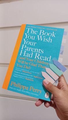 the book you wish your parents had read is being held up by someone's hand