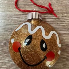 a gold ornament with a smiling face on it's side and red string