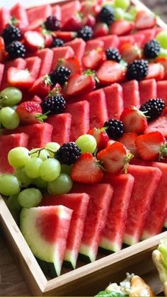 watermelon, grapes and blackberries are arranged on a platter for a party