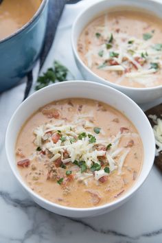 two bowls of soup on a marble table with bread and parmesan sprinkles