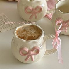 two mugs with pink bows are sitting on a table