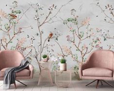 two pink chairs sitting next to each other in front of a wall with flowers and birds on it