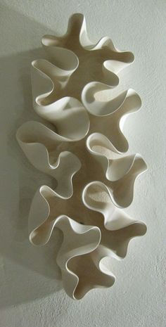 a white sculpture is hanging on the wall