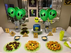 an alien themed birthday party with green balloons and desserts on the dining room table