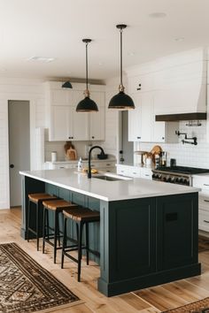 a kitchen with an island and stools next to it on a rug in the middle of the floor