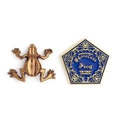 a gold frog brooch sitting next to a blue and white pin with the words, gorgoffe's roost on it