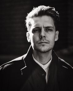 a black and white photo of a man wearing a shirt and tie with his eyes closed