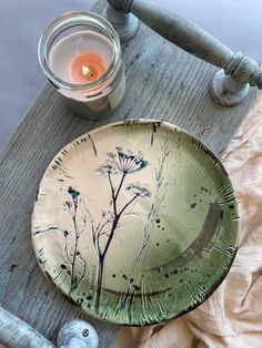 a plate sitting on top of a wooden table next to a candle