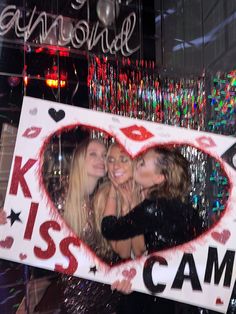 three women are posing in front of a photo frame with the words kiss camo on it