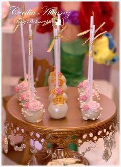 there are four candles that are on the cake stand with pink flowers and gold trimmings