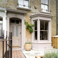 the front entrance to a brick building with potted plants