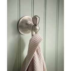 a towel hanging on the side of a green wall next to a metal door handle