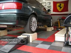 a car is on the lift in a garage with checkered flooring and other tools