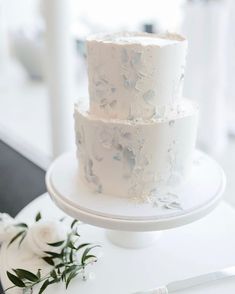 three tiered white cake sitting on top of a table