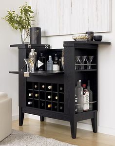 a black bar with wine glasses and bottles on it in front of a white wall