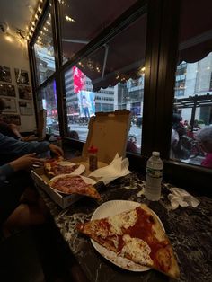 two slices of pizza sitting on top of a table in front of a large window