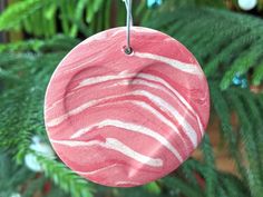 a pink and white ornament hanging from a christmas tree