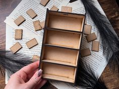 a person is holding a box with several pieces of cardboard in it on top of an open book