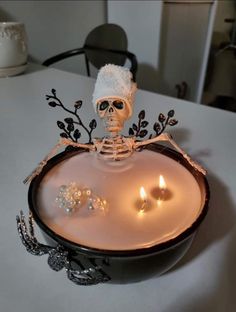 a skeleton in a hat is sitting on a tray with candles and some other decorations