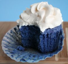 a blue cupcake with white frosting on a plate