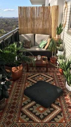 a balcony with potted plants and rugs on the floor, next to a couch