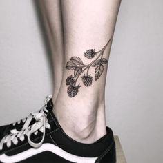 a woman's foot with a small tattoo on the side of her leg that has berries and leaves on it